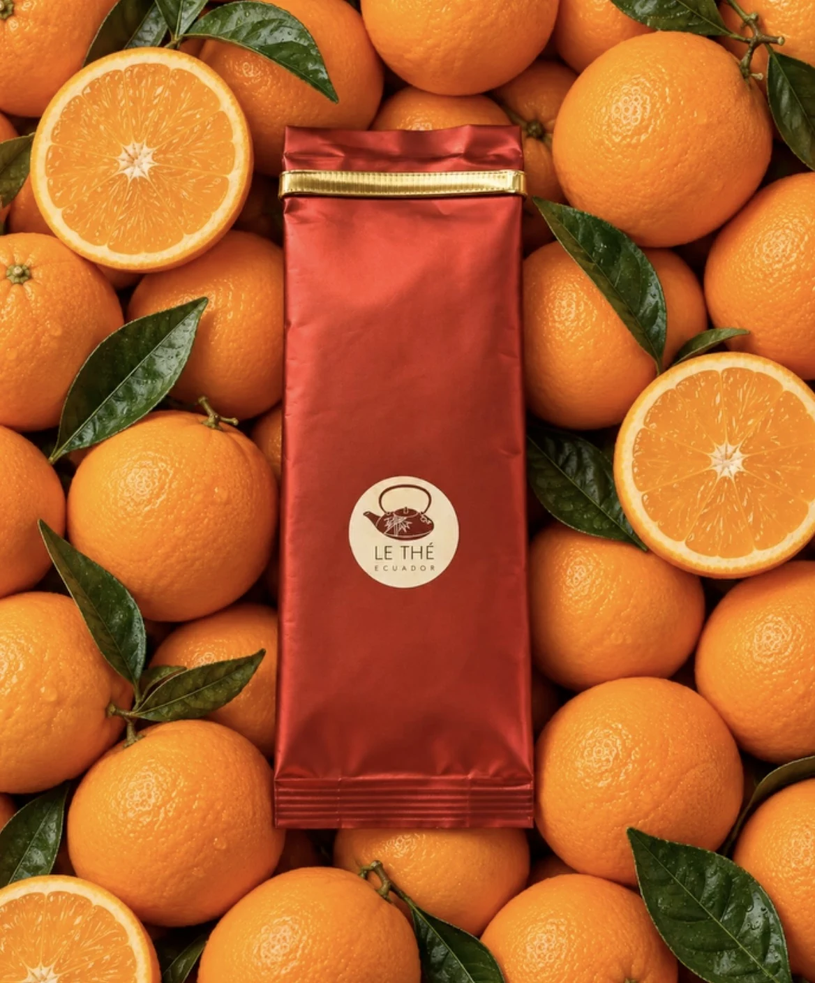 Empaque rojo de Le Thé sobre una composición de naranjas frescas