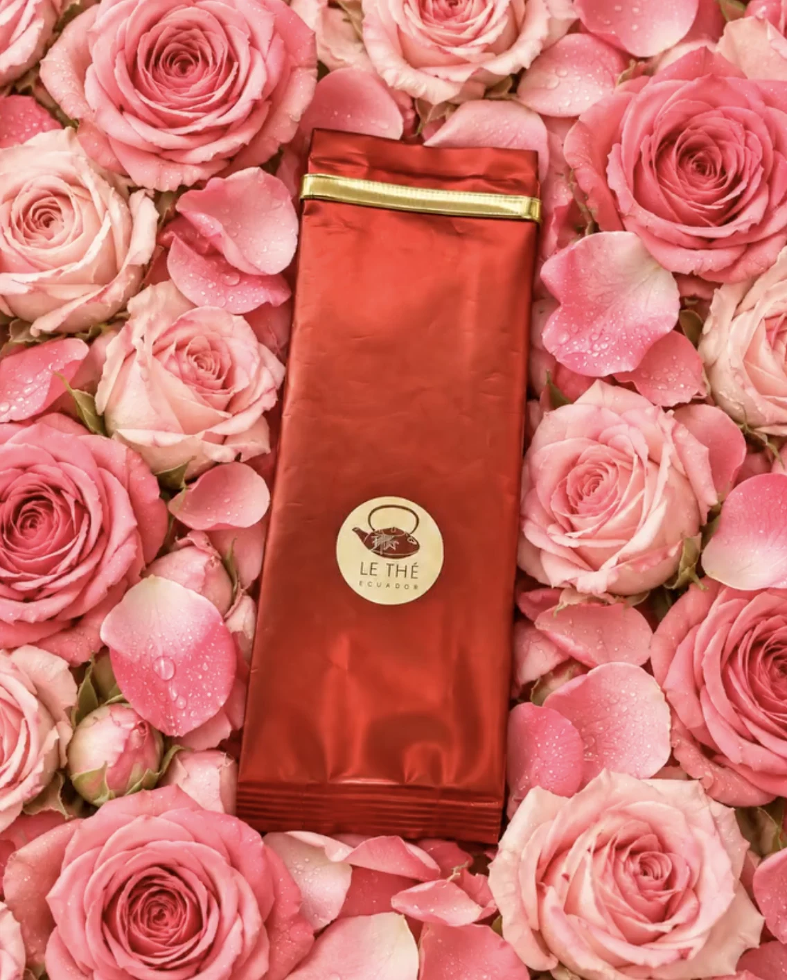 Empaque rojo de Le Thé entre rosas rosadas